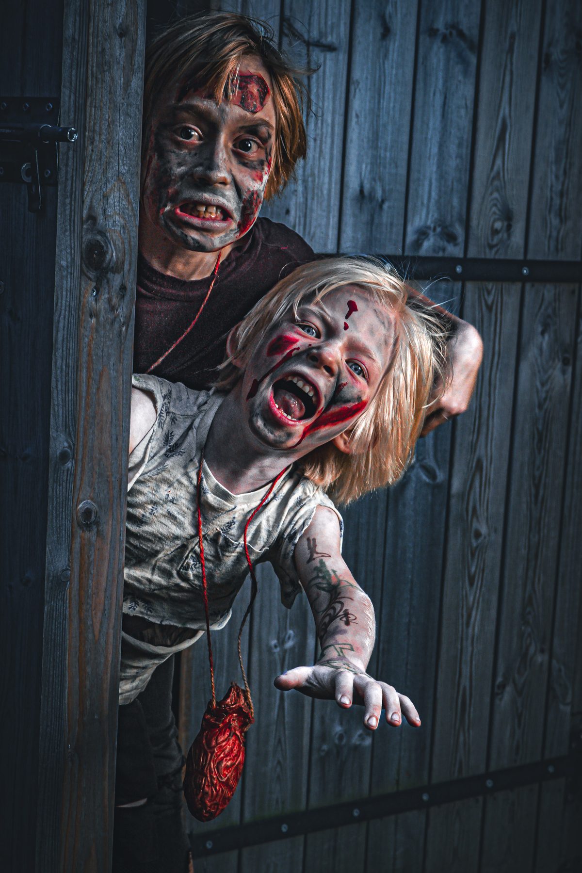 One zombie peering round a door while the other lunges out with bloody hands.
