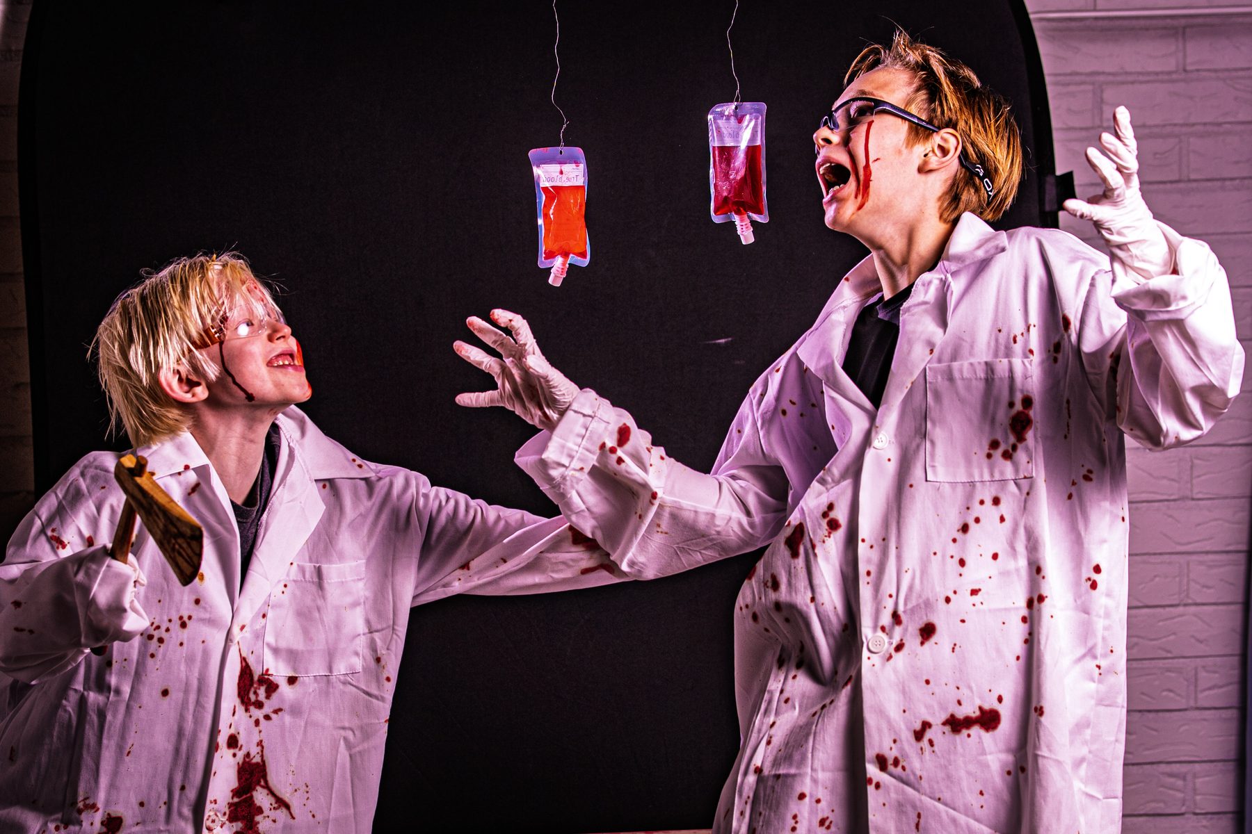The younger scientist, axe in hand, reaching for the blood bags while the older one screams at them.