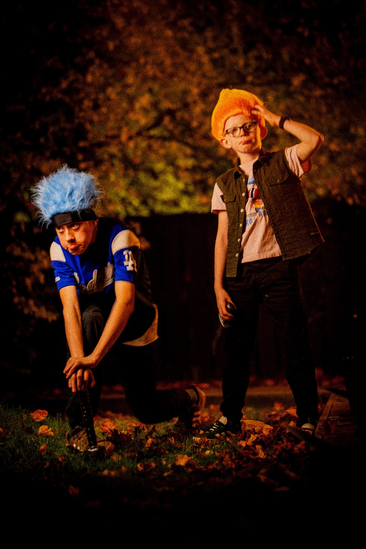 Blue troll kneeling and pouting, orange troll scratching his wig.